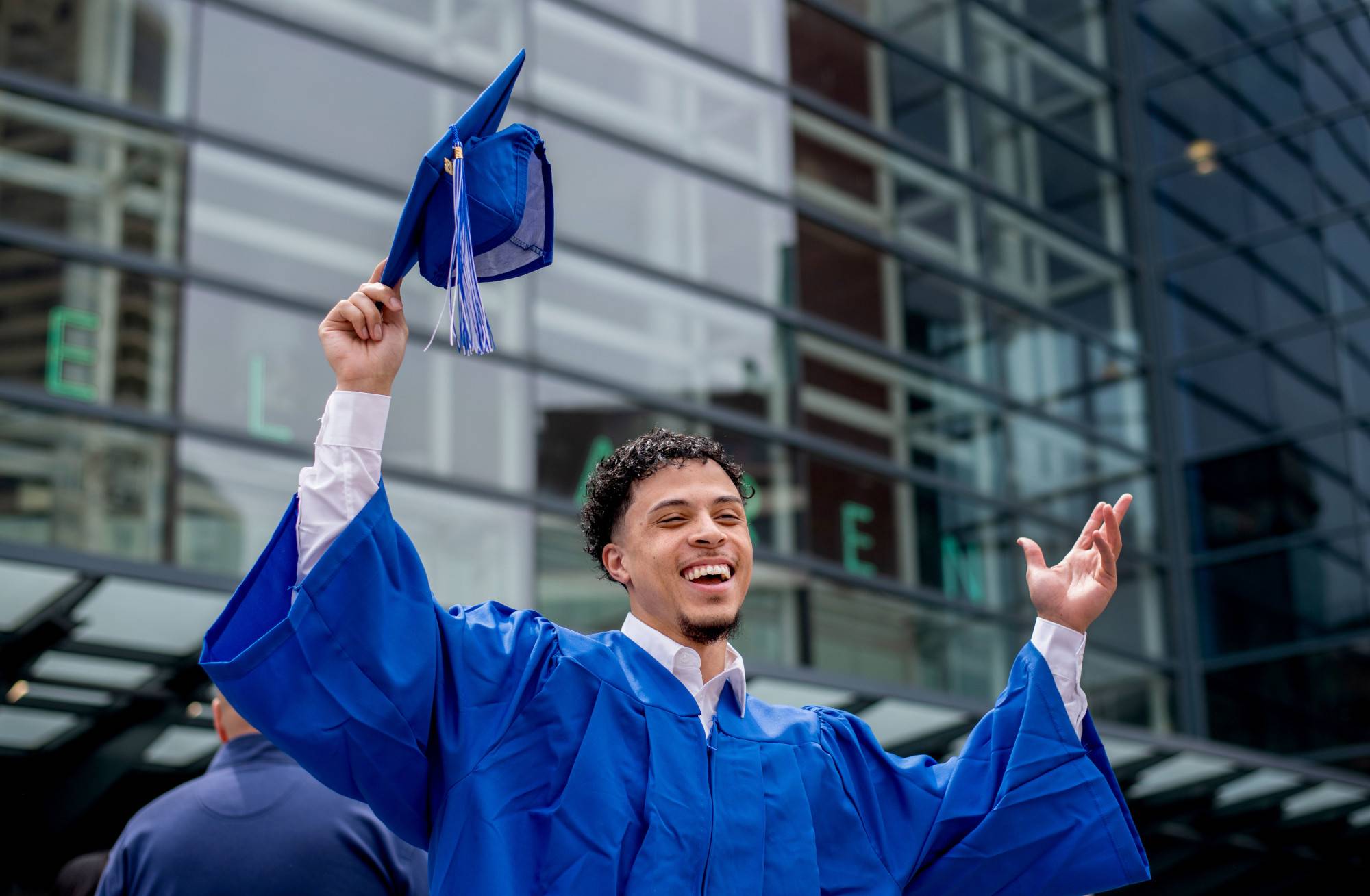 A grad celebrates with his cap raised outside Van Andel arena